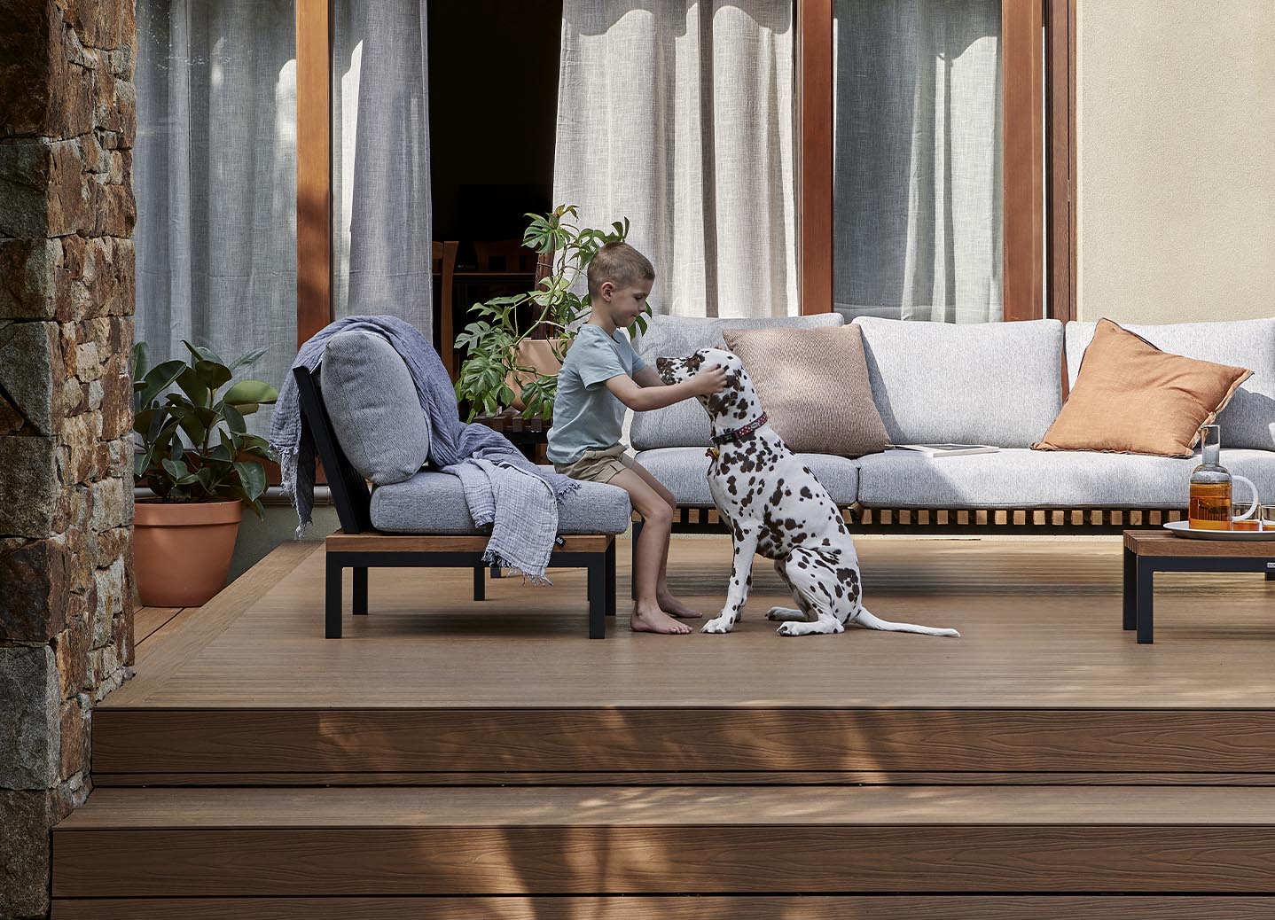 A young boy and a dalmatian on a wooden composite decking.