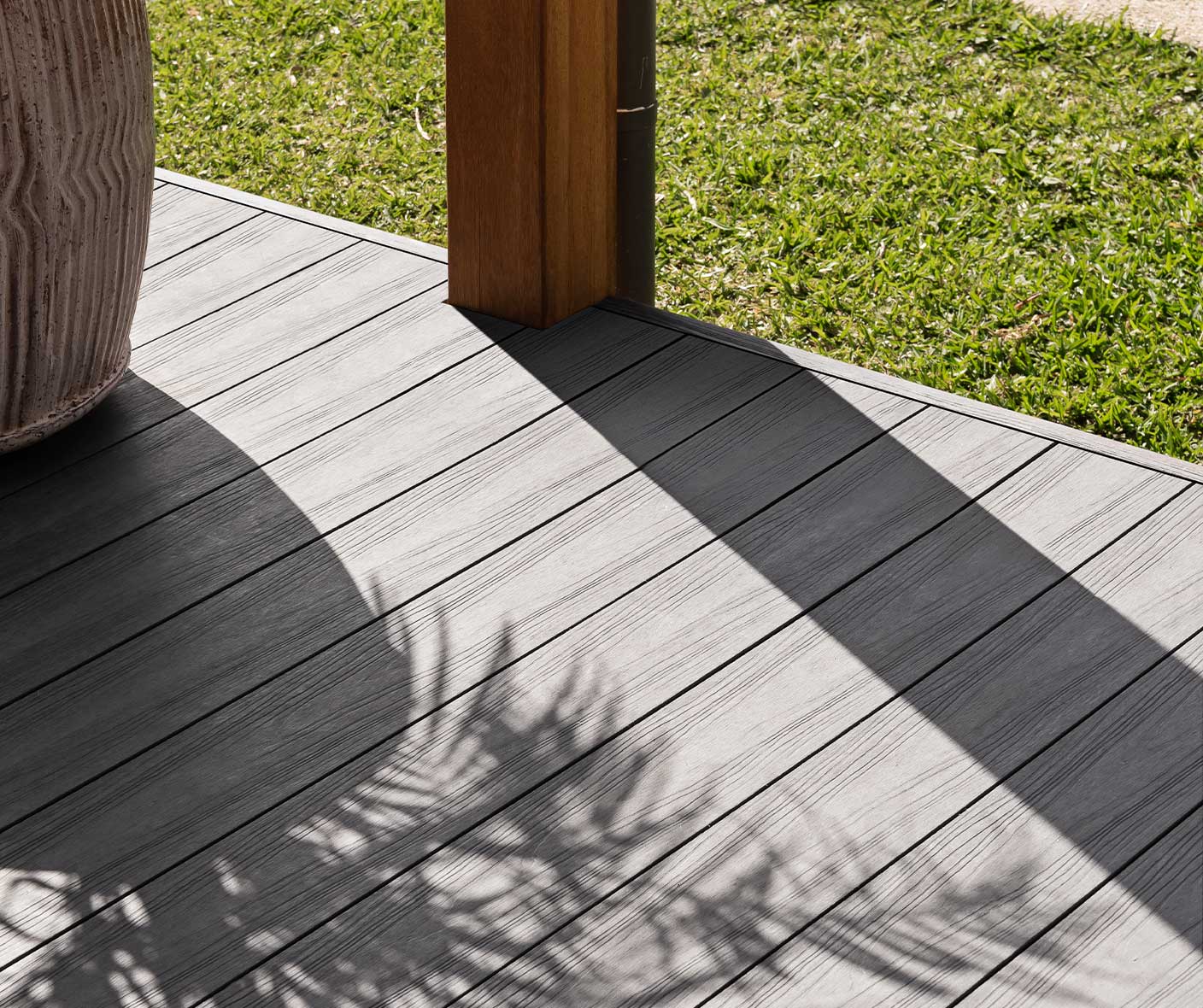 A wooden deck with a potted plant on it, constructed using composite decking.