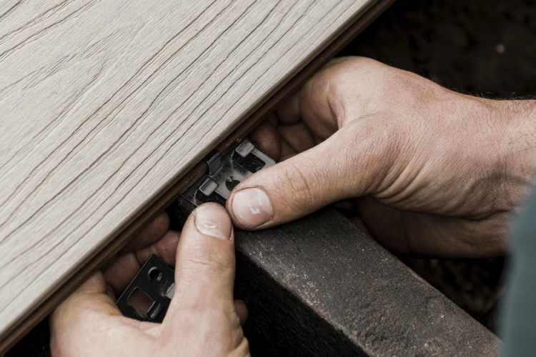 A person is working on a composite decking plank.