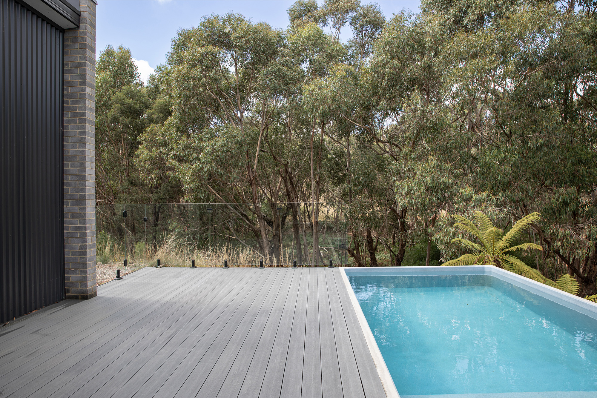 A swimming pool with composite decking and trees.