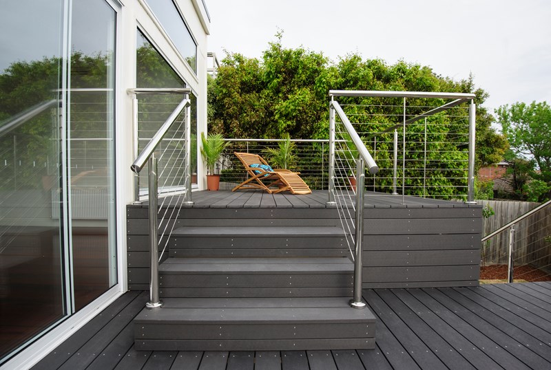 A deck made of composite decking material, complete with a sturdy railing and a comfortable chair.