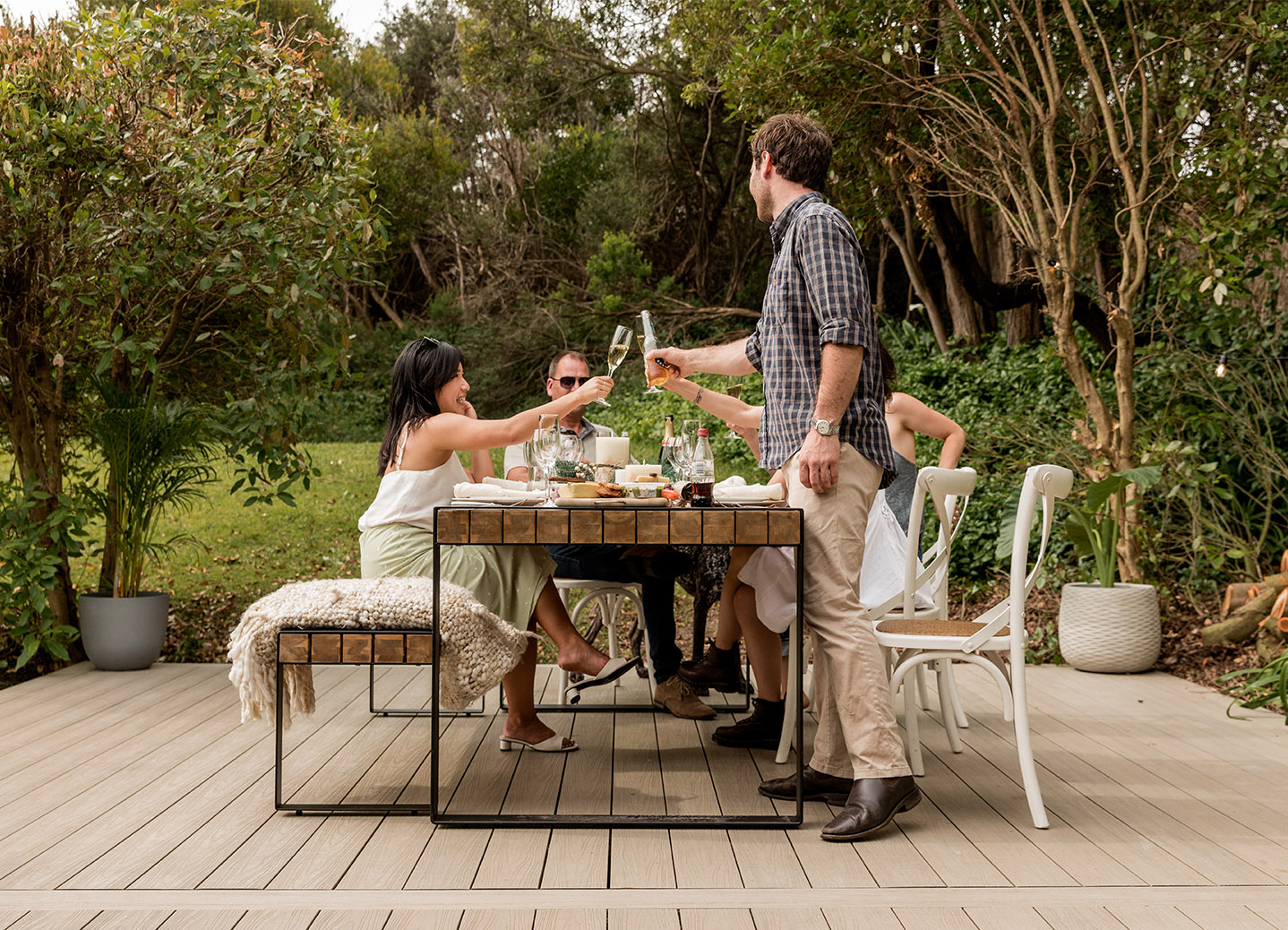 A group of people toasting at a table with composite decking in a backyard.