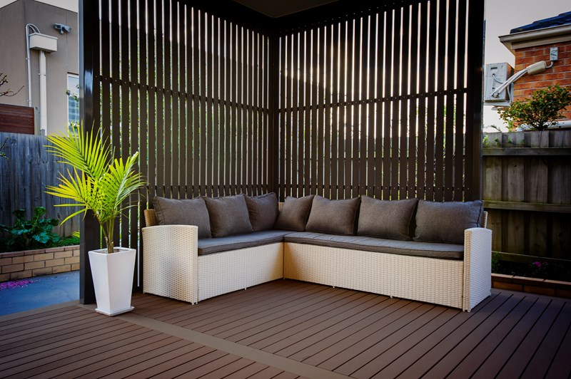 A wooden deck with a couch and a potted plant made of composite decking.